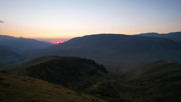 Red rays of the sun at sunset among the mountains