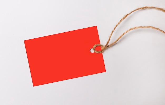 Red rectangular empty price tag with place to insert text on a string on a white background Copy space