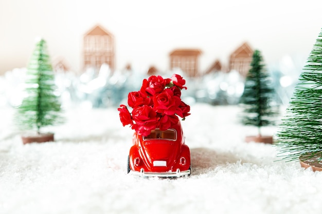 Red retro car with flowers in a winter landscape Flower delivery for the holiday