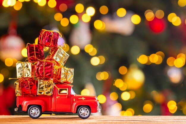 Photo red retro toy truck carries gifts on the background of christmas tree