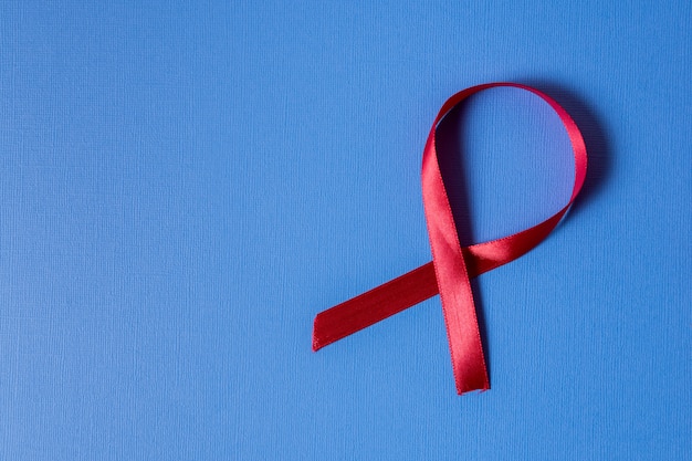 Red ribbon breast cancer awareness on blue background 