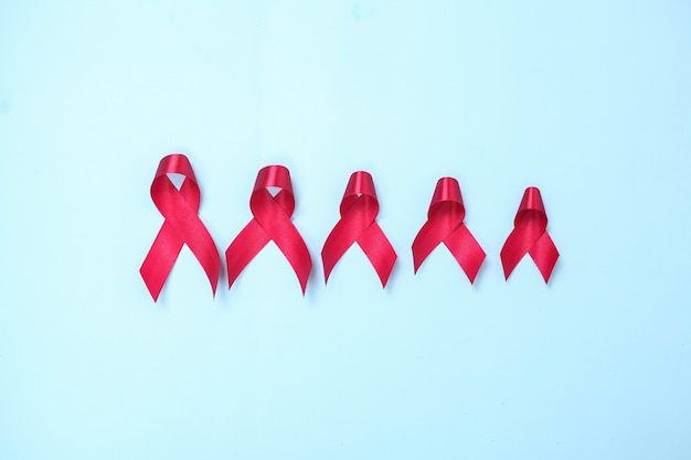 Red ribbon composed of symbols of AIDS against HIV virus isolated on blue background