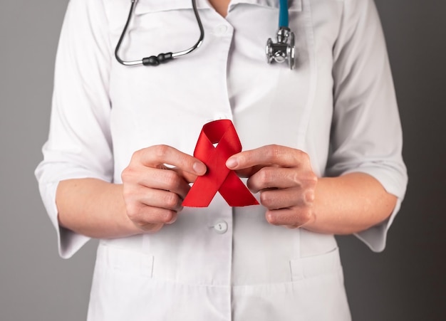 Red ribbon in doctors hand symbol of HIV and AIDS awareness day 1 December support