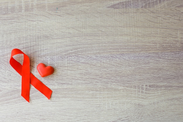 Photo red ribbon hiv aids and heart shape for blood symbol on wooden background world aids day