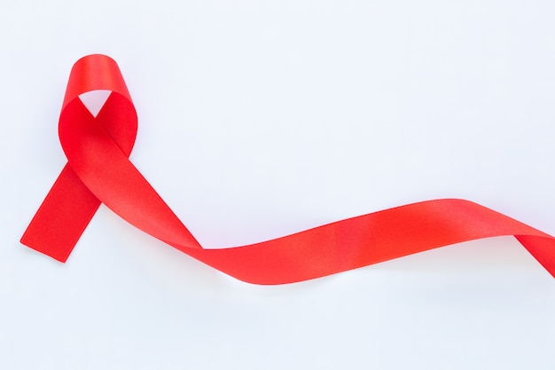 Red ribbon on white fabric table with copy space symbol for the solidarity of people living with HIVAIDS and for the awareness and prevention of drug abuse and drunk driving Health concept