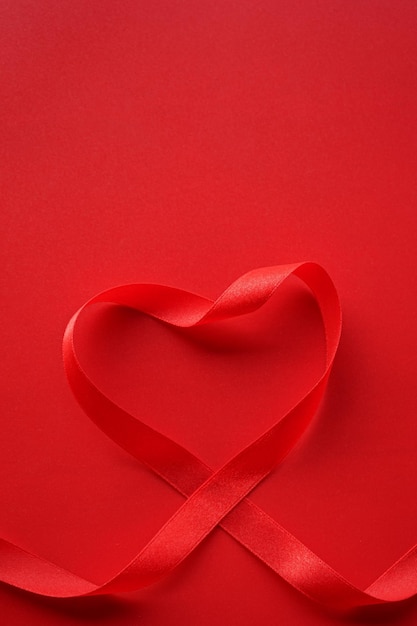 Red ribbon with heart shape on red background Valentines day Or Love background concept