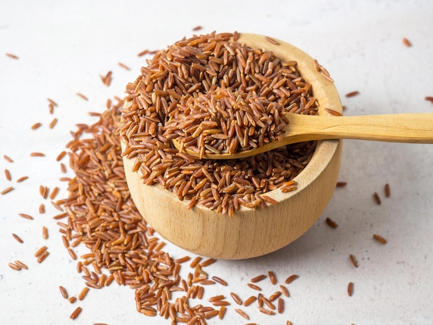 Red rice brown rice in a wooden bowl red rice scattered on the groundclose up