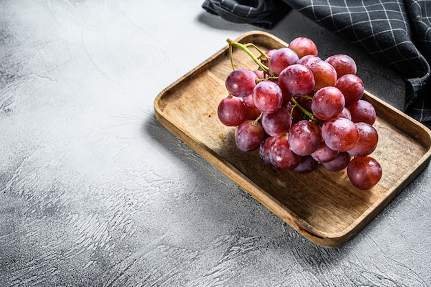 Red ripe grapes in a wooden bowl. White background. . 