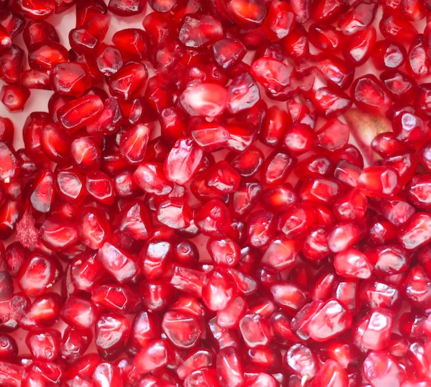 Red ripe pomegranate grains on white background.