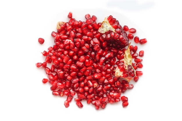 Red ripe pomegranate grains on white background.