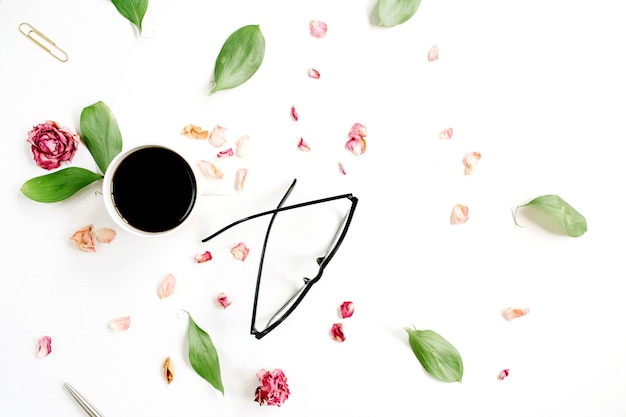 Red rose bud, glasses, leaves, coffee on white surface