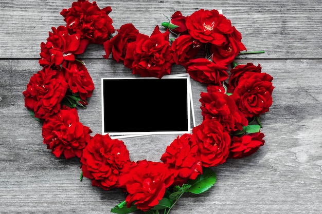 Red rose flowers heart shaped with blank photo frame on rustic wooden table