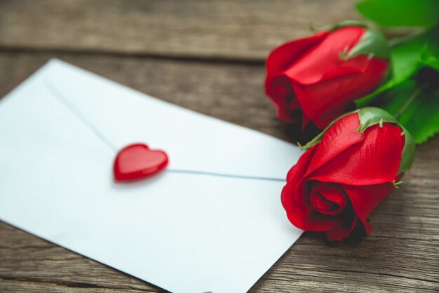 Red rose flowers and letter on wood table