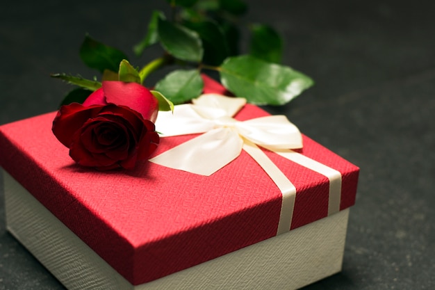 Red rose with gift box on dark background 