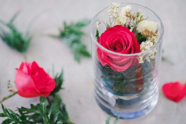 Red roses and decorative leaves in glass are beautifully arranged on the table