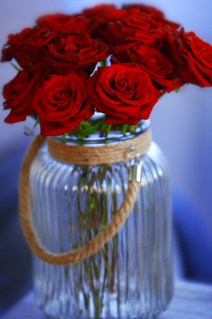 Red roses in a glass jar in the room