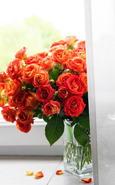 Red roses in a glass vase on the window sill