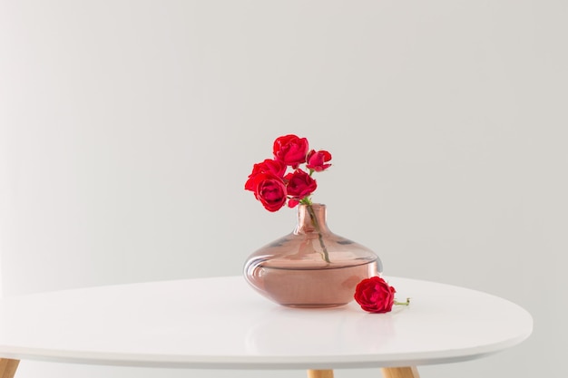 red roses in modern glass vase in white interior