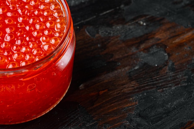 Red salmon caviar jar, on old dark  wooden table background  with copy space for text