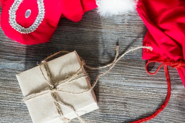 Red Santa Claus mittens and a box with gifts in craft packaging on a wooden surface