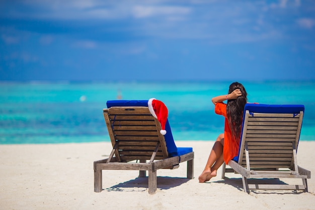 Red santa hat on chair longue at tropical white beach