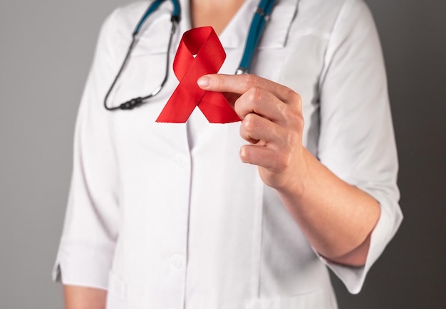 Red satin ribbon in doctors hand symbol of HIV and AIDS awareness day 1 December support