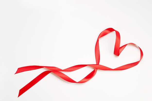 Red satin ribbon in the form of a heart on a white background