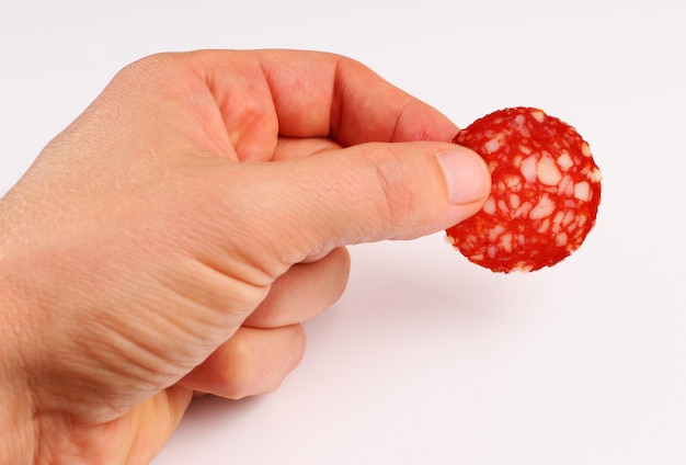 Red sausage in hand on a white surface