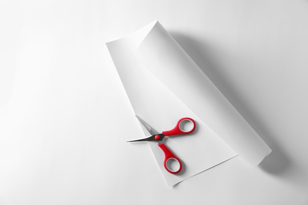 Red scissors and paper on white background top view Space for text