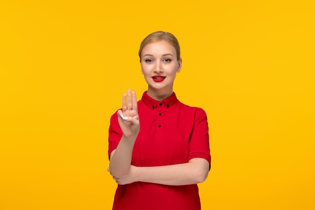 Red shirt day cute girl showing three fingers in a red shirt on a yellow background