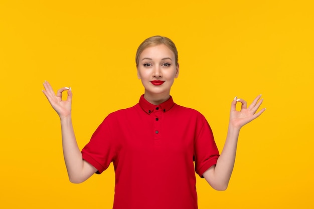 Red shirt day happy girl showing zen sign gesture in a red shirt on a yellow background