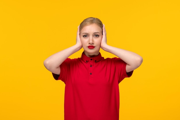 Red shirt day pretty girl covering her ears in a red shirt on a yellow background