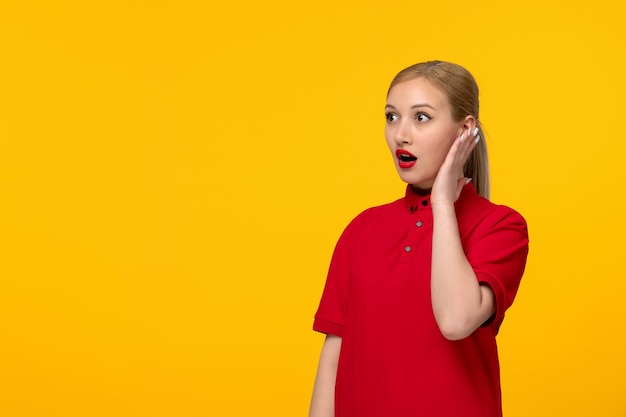 Red shirt day shocked girl holding her head in a red shirt on a yellow background