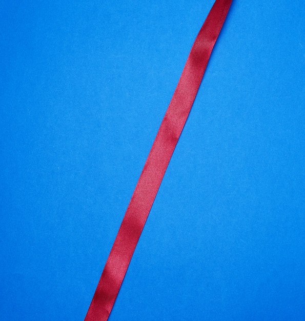 Photo red silk thin ribbon on a blue surface