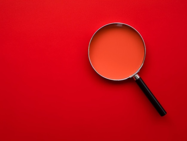 A red and silver magnifying glass with a black circle on the top.