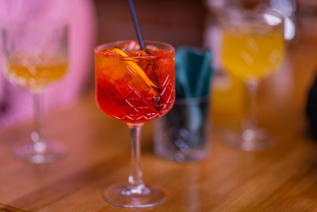 A red sour cocktail in a coupe glass decorated with a fir branch on the table in a bar