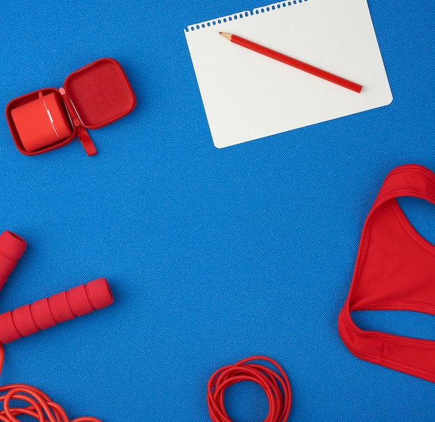 Photo red sports shirt, red jump rope and wireless headphones