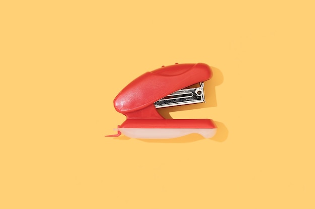 Red stapler on a yellow background Stationery and school supplies