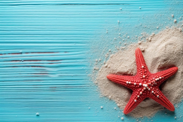 A red starfish sits on a blue table with sand on it.