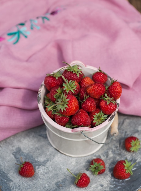 Red strawberies in a white bowl on the blue stone table