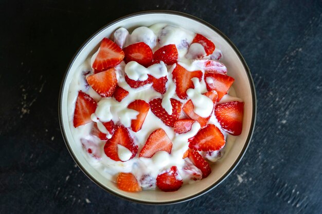 Red strawberry and white yogurt brulee Fruit dessert on breakfast with wedges of perfectly ripe in season strawberry closeup