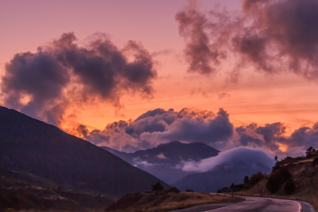 Red sunset in the mountains with big white clouds.