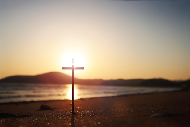 The red sunset on the seashore and the sandy beach with strong light reflections and the Holy Cross