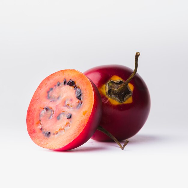 Red Tamarillo with a slice over white background