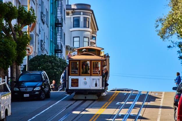 Red and tan trolley streetcar at top of hill heading down with apartment buildings behind San Franc