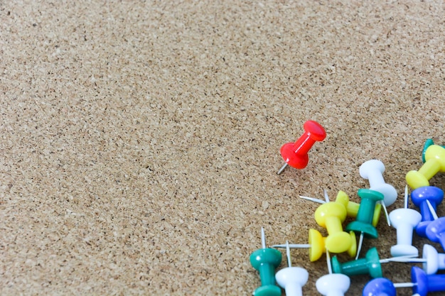 Red thumbtack pinned on corkboard