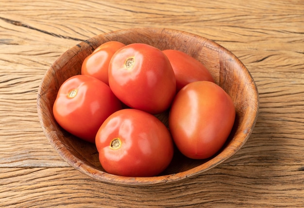 Red tomatoes in a bowl over wooden table