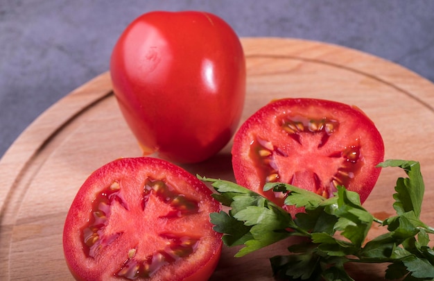 Red tomatoes on a chopping board with a sprig of parsley