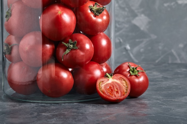 Red tomatoes in a glass vase on a gray background