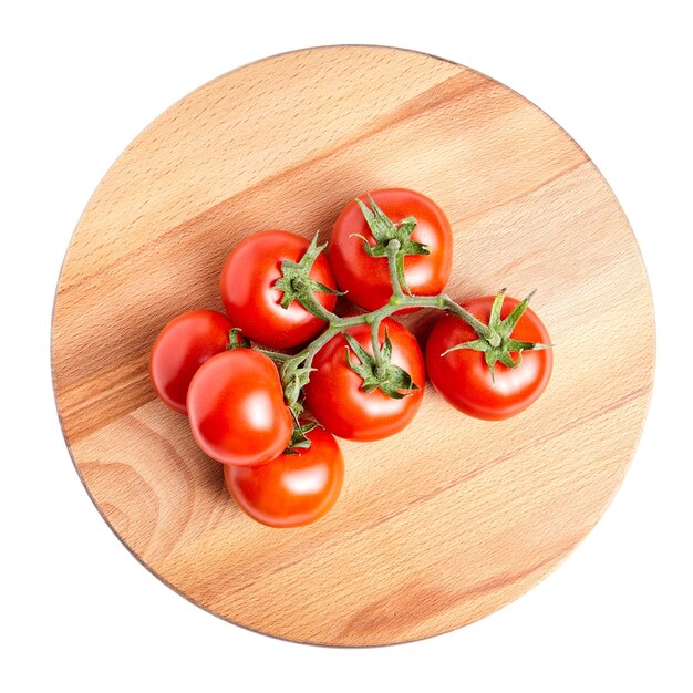 Red tomatoes on a green branch laying on wooden beech board, fresh vegetable isolated on white background